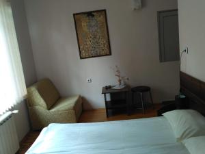 um quarto com uma cama, uma cadeira e uma mesa em семеен хотел "НЕВЕН" em Momin Prohod