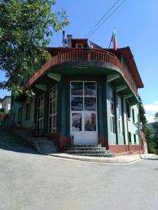 um edifício verde e branco com um alpendre em семеен хотел "НЕВЕН" em Momin Prohod