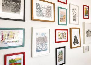 a wall of framed pictures on a wall at Travel & Live Porto Hostel in Porto