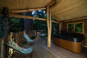 eine Veranda einer Hütte mit einem Whirlpool und Stühlen in der Unterkunft Domaine de la Font Vineuse & Spa in Saint-Pierre-dʼArgençon