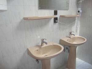 ein weißes Badezimmer mit einem Waschbecken und einem Spiegel in der Unterkunft Gyöngyvirág Vendégház in Balatonboglár