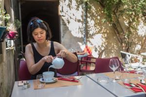 Uma mulher está sentada numa mesa com um copo. em Les suites de Peyrat em Pézenas