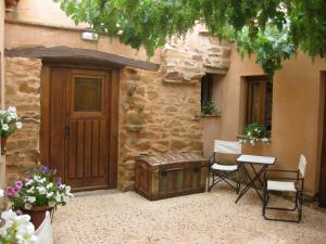 ein Gebäude mit einer Holztür, einem Tisch und Stühlen in der Unterkunft Casa Rural Las Águedas in Murias de Rechivaldo