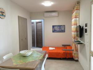 ein Wohnzimmer mit einem orangenen Bett und einem Tisch in der Unterkunft Casa Vacanza Demi in Alcamo Marina