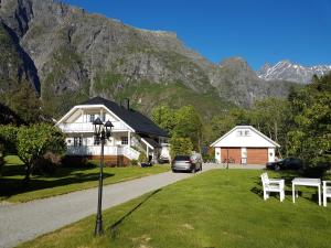 a house and a car on a road with mountains in the background at Nora Gård in Åndalsnes