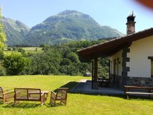 un grupo de bancos sentados fuera de una casa con montañas en Eguzkitze Alojamiento Rural LSS00085 en Abaltzisketa