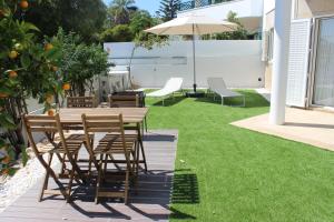 a patio with a table and chairs and an umbrella at Encosta´s Garden in Oeiras