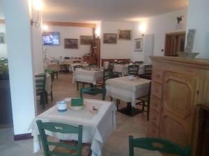 um restaurante com mesas e cadeiras brancas e um quarto em Hotel Garni Al Nardis em Carisolo