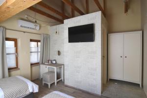 una camera da letto con TV su un muro di mattoni bianchi di Janez Rooms a Lubiana