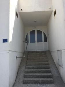 a hallway with stairs leading to a white door at Apartment Subota in Mali Lošinj