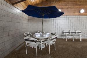فندق Americinn في Mounds View: طاولة مع كراسي ومظلة زرقاء في الغرفة