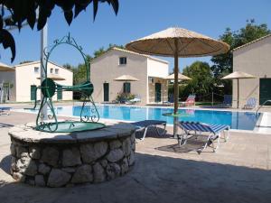 a swimming pool with a fountain and an umbrella at Rania Studios in Lefkada