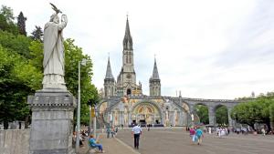 eine Statue vor einem Gebäude mit einer Kathedrale in der Unterkunft Le petit nid in Lourdes