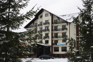 ein Gebäude, vor dem ein Auto geparkt ist in der Unterkunft Hotel Crisalpin in Poiana Brașov