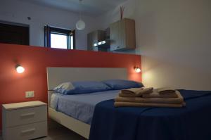 a bedroom with a bed with blue sheets and an orange wall at Albizia, casevacanza in Agropoli