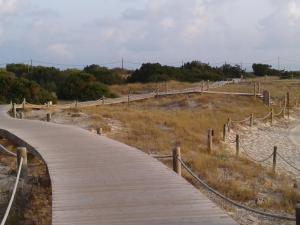 a wooden boardwalk on the side of a beach at Hotel Roca Bella in Es Pujols