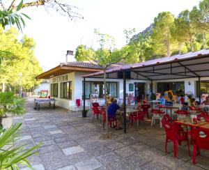 eine Terrasse mit roten Stühlen und Tischen sowie ein Gebäude in der Unterkunft Lago Resort in Nuévalos