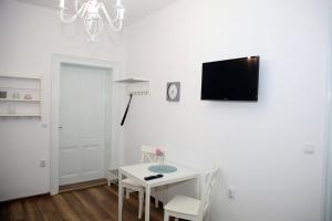 a white dining room with a table and a tv on a wall at Schick apartment in Sibiu