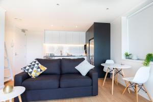 a living room with a blue couch and a kitchen at Brand New Auckland Apartment in Auckland
