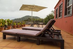 a pair of chairs and an umbrella on a balcony at Country house Santa Lucia in Puntallana