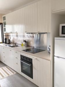 a white kitchen with a stove and a refrigerator at Apartamento - Casas dos Infantes in Caldas da Rainha