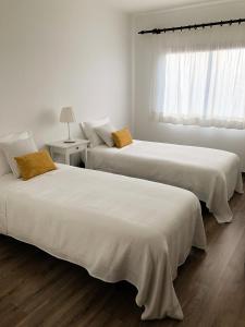 two beds in a white room with a window at Apartamento - Casas dos Infantes in Caldas da Rainha