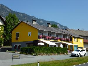 a yellow building with a car parked in front of it at Gailtal Inn in Förolach