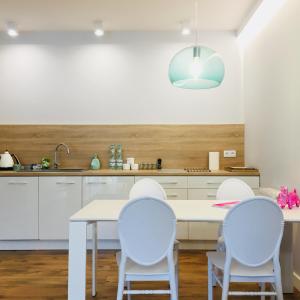 a kitchen with white cabinets and a white table and chairs at Piper Zajezdnia White in Poznań