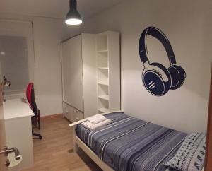 Schlafzimmer mit einem Bett mit Kopfhörern an der Wand in der Unterkunft Betiko in Vitoria-Gasteiz