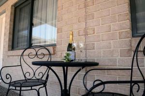 uma mesa com uma garrafa de vinho e duas cadeiras em Oakey Motor Inn em Oakey