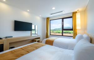 a hotel room with two beds and a large window at Thira Hotel in Seogwipo