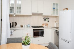 a kitchen with white cabinets and a table with a plant at Kidd Street Cottages in Mount Tamborine