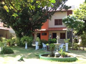 a garden with a table and chairs in front of a house at Hotel Jardim in Fortaleza