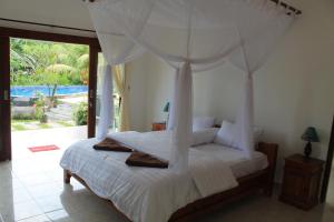 a bedroom with a white bed with a canopy at Villa Mangga Beach in Amed