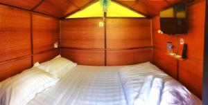 Cette petite chambre comprend un grand lit et des murs en bois. dans l'établissement Kea Garden Mini Chalet, à Cameron Highlands