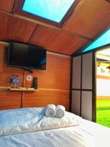 a bedroom with a bed with a tv and towels at Kea Garden Mini Chalet in Cameron Highlands