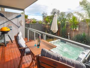 terraza con mesa de madera y bañera de hidromasaje en Seagrass Villas Normanville, en Normanville