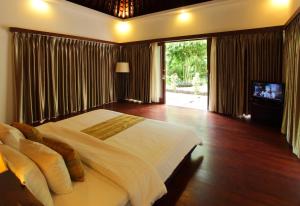 a bedroom with a large bed and a television in it at Kebun Villas & Resort in Senggigi