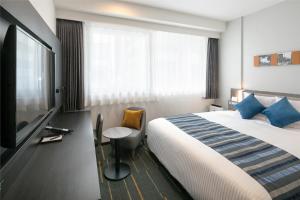 um quarto de hotel com uma cama e uma televisão de ecrã plano em Hotel Mystays Nagoya Nishiki em Nagoia