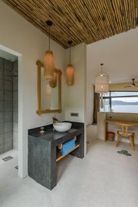 a bathroom with a sink and a mirror at Que Toi Village Resort Phu Yen in Song Cau