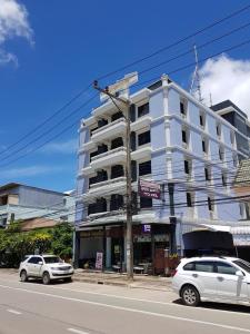 due auto parcheggiate di fronte a un edificio bianco di Grand Mansion Hotel a Krabi town