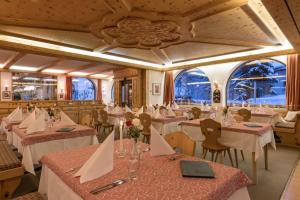 un restaurante con mesas y sillas blancas y ventanas en Hotel Seraina, en Sils-Maria