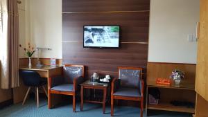 ハイフォンにあるPhuong Anh 3 Hotelの椅子2脚、テーブル、壁掛けテレビが備わる客室です。