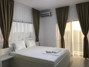a bedroom with a white bed with a window at Casa Decebal in Eforie Nord