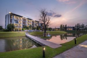 a building with a bridge next to a pond at Green Ville Laguna Hotel in Sung Noen