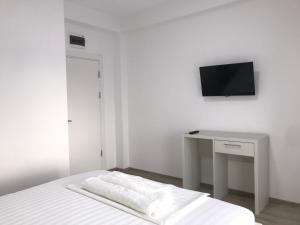 a white bedroom with a bed and a desk with a television at Casa Decebal in Eforie Nord