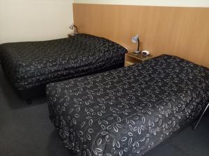 2 letti in una camera d'albergo con copriletto nero di Clifton Motel ad Albury