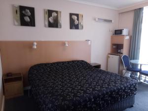 a bedroom with a bed, desk and a painting on the wall at Clifton Motel in Albury