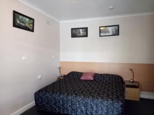 a bedroom with a bed and three pictures on the wall at Clifton Motel in Albury