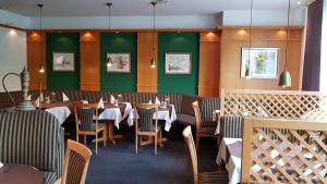a dining room with tables and chairs and green walls at Hotel & Restaurant Fricke in Hämelerwald